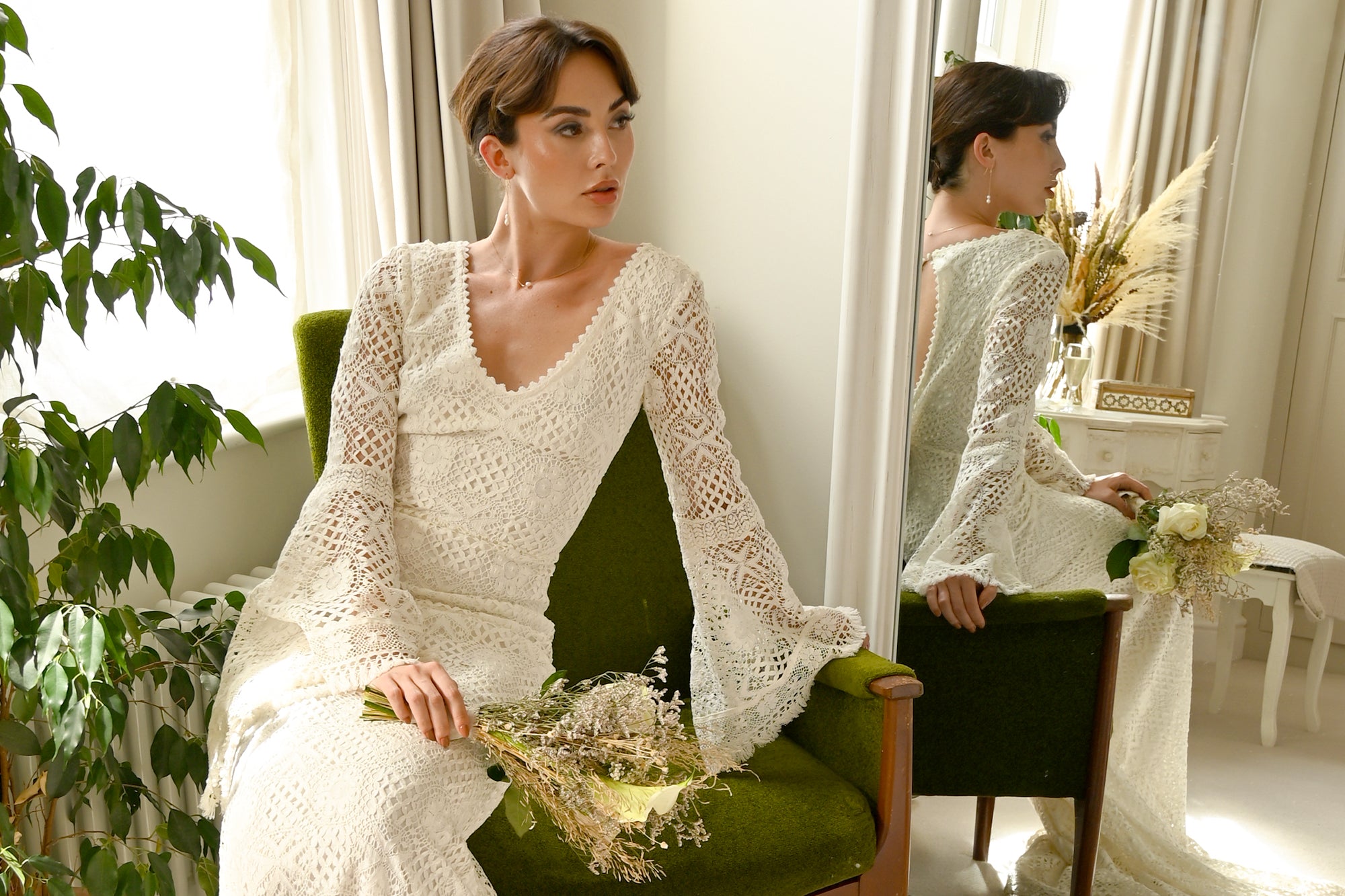 bride in lace gown wearing bridal jewellery and holding a bouquet of flowers