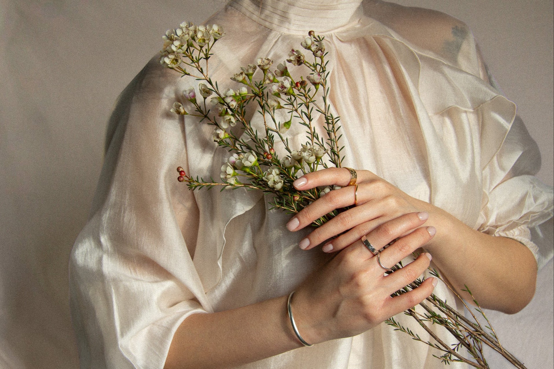 model wearing silk shirt and valentines gold and silver jewellery holding flowers 